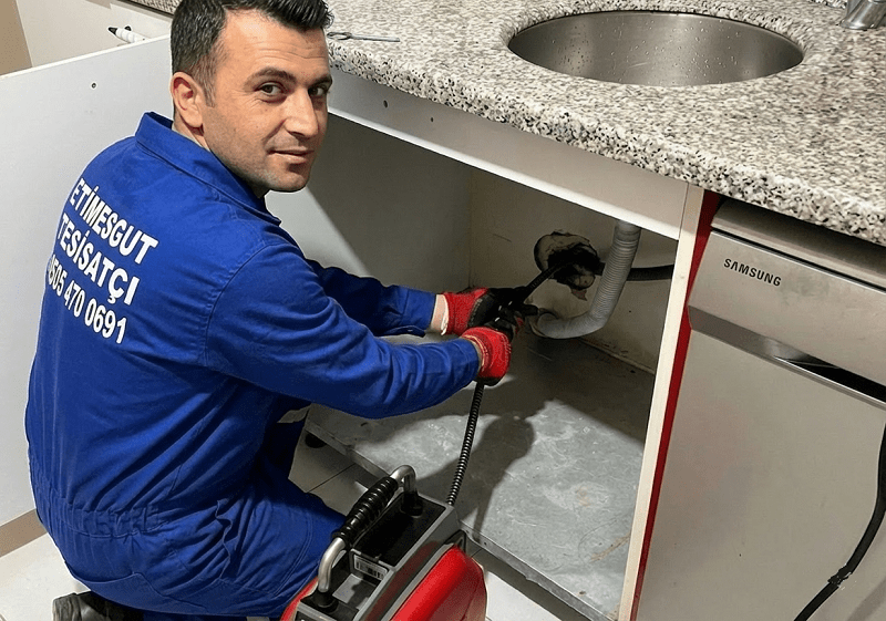 Etimesgut Tesisatçı Ada Tesisat üniformalı usta mutfak lavabosu altındaki tıkanıklığı robot makine ile açarken